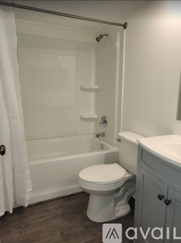 A white toilet in a bathroom with a white shower curtain.