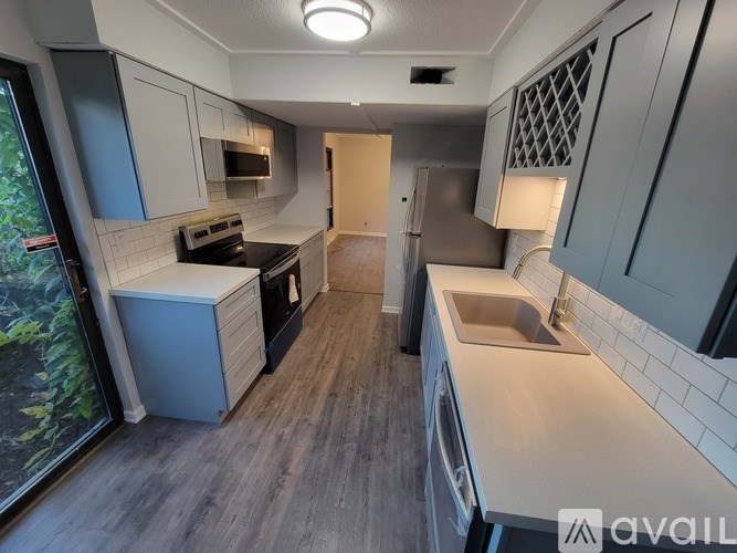 A kitchen with a sink, stove, and cabinets.