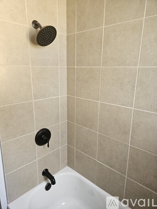 A white bathtub with a black shower head and faucet.