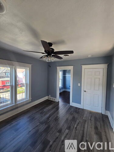 A room with a ceiling fan and wooden flooring.
