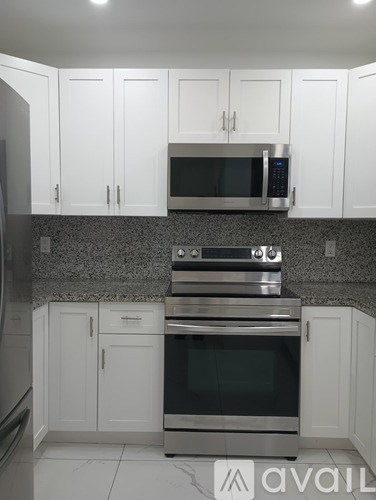 A kitchen with white cabinets and a granite countertop.