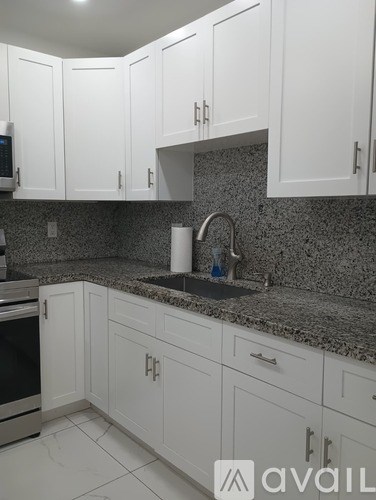 A kitchen with white cabinets and a granite countertop.