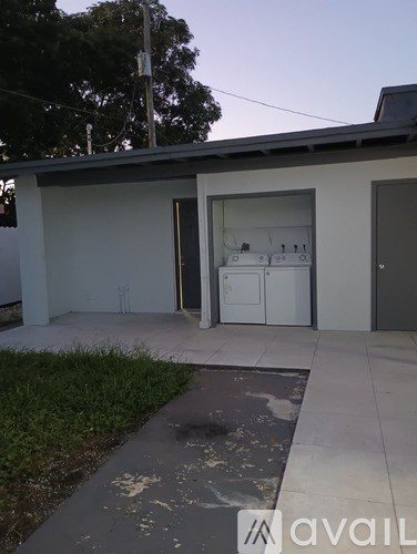 A white building with a door open to a laundry room.
