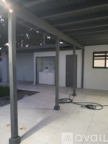 A patio area with a white tile floor and a white wall.