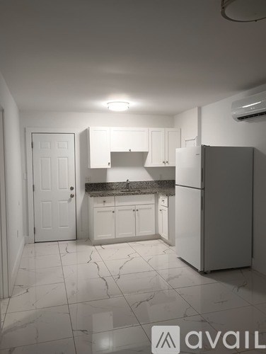 A kitchen with white cabinets and a marble floor.