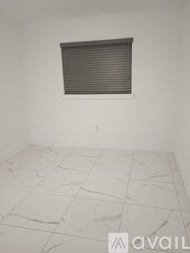 A room with a marble floor and a window with blinds.