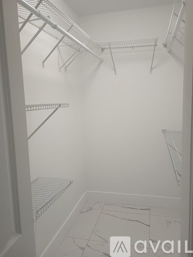 Empty white walk in closet with shelves.