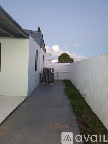 A white fence runs along the side of a building.
