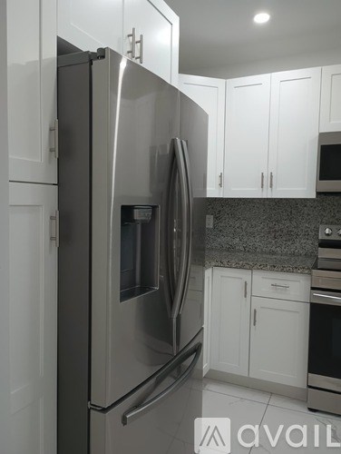 A stainless steel refrigerator in a kitchen with white cabinets.