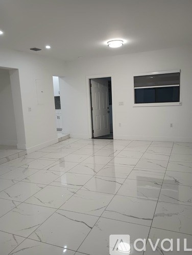 A spacious room with white marble flooring and a closed door.