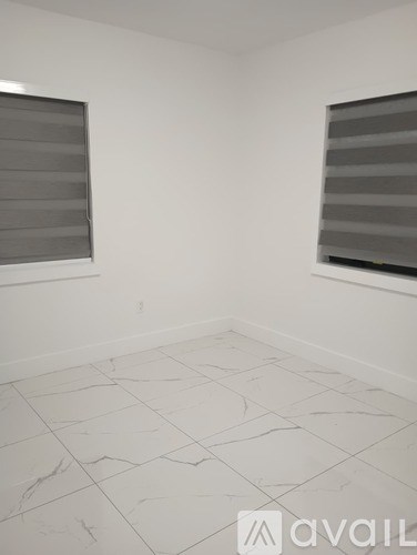 A room with a tiled floor and two windows with blinds.