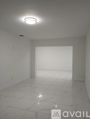 A room with white tiled flooring and a single light fixture on the ceiling.