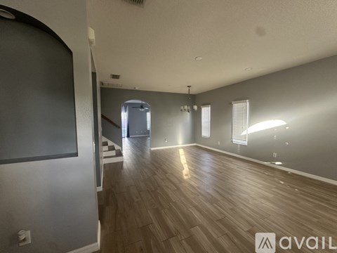 A spacious room with wooden flooring and a staircase leading to another room.