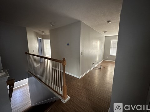 A room with wooden floors and a staircase with a wooden railing.