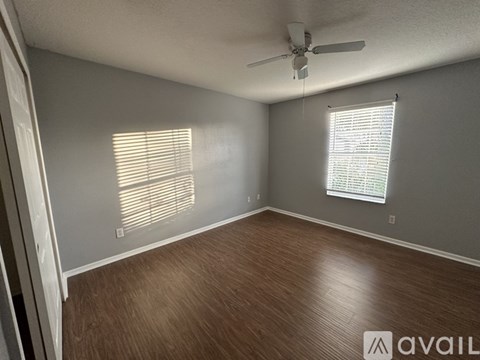 A room with a ceiling fan and wooden flooring.