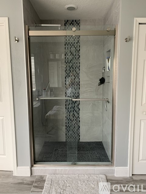 A bathroom with a glass shower door and a white door.