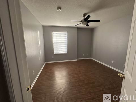A room with a ceiling fan and wooden flooring.