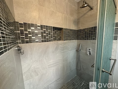 A bathroom with a walk-in shower and a glass door.