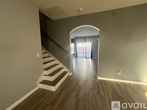 A room with a staircase and a doorway leading to another room.