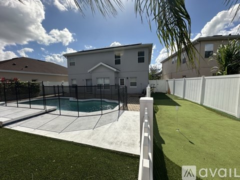 A house with a pool and a white fence.