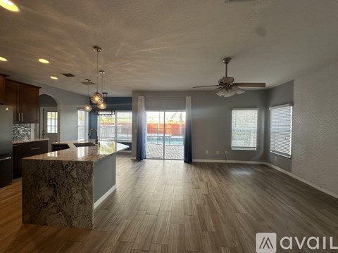A spacious living room with a marble island in the center and a ceiling fan.