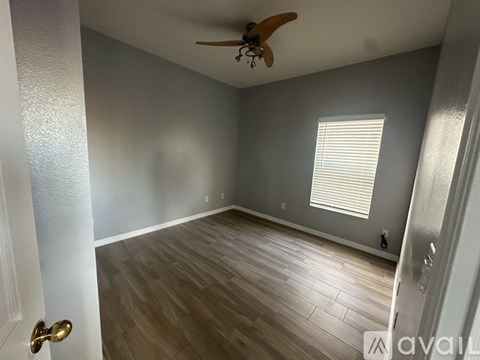 A room with a ceiling fan and wooden flooring.