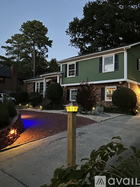 A house with a green exterior and a driveway with a yellow sign.