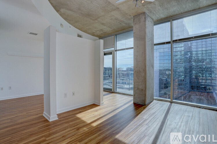 A spacious room with wooden floors and large windows overlooking a cityscape.