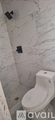 A white toilet in a bathroom with marble walls.