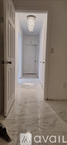 A hallway with marble flooring and a chandelier.