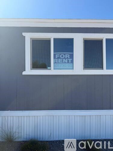 A house with a window that has a for rent sign.
