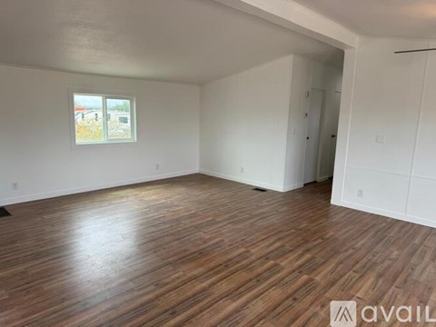 A spacious room with wooden flooring and white walls.