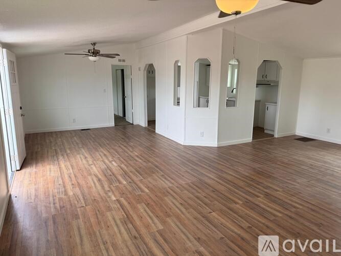 A spacious room with wooden flooring and a ceiling fan.