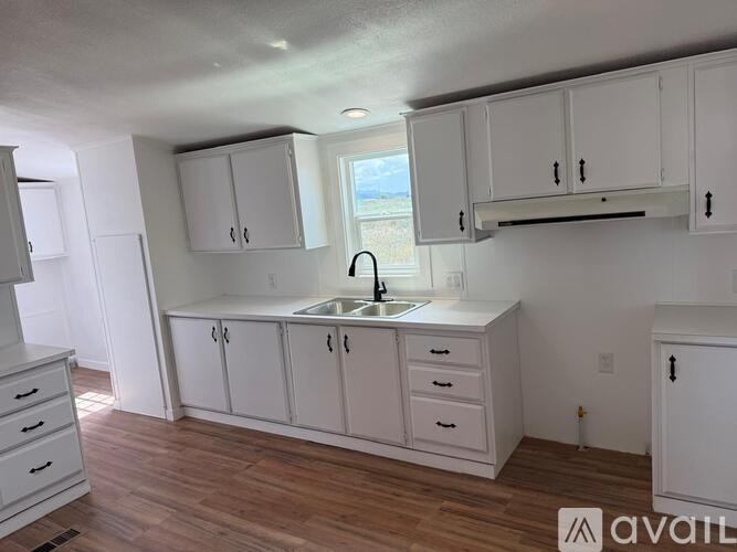 A kitchen with white cabinets and a wooden floor.