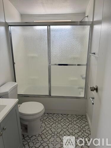 A white toilet sits in a bathroom with a glass shower door.