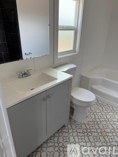 A white toilet sits in a bathroom with a black and white floor.