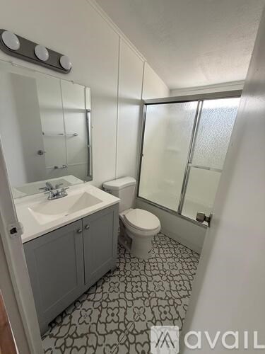 A bathroom with a sink, toilet and mirror.