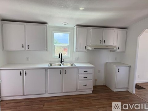 A kitchen with white cabinets and a window overlooking a lawn.