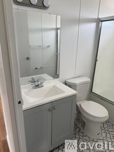 A bathroom with a sink, toilet and mirror.
