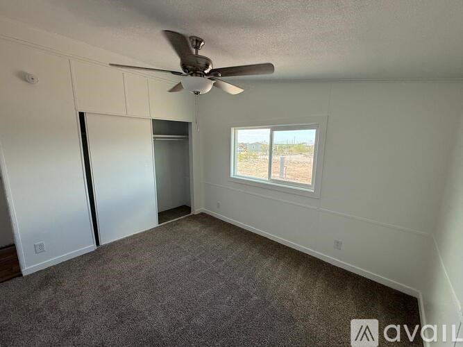 A room with a ceiling fan and a window overlooking a desert landscape.