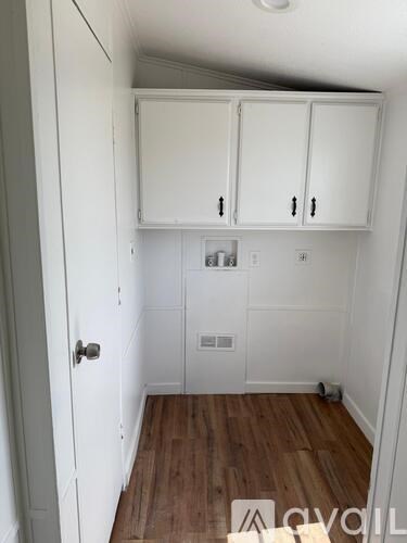 A small room with white cupboards and wooden flooring.