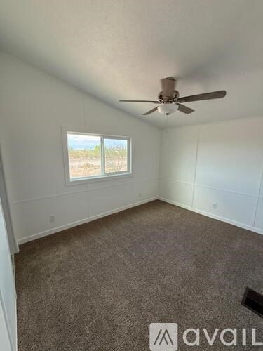 A room with a ceiling fan and a window overlooking a desert landscape.