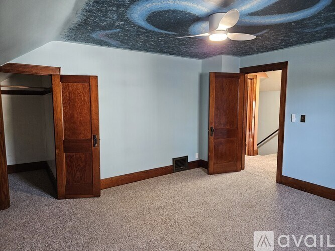 A room with a ceiling fan and two doors.