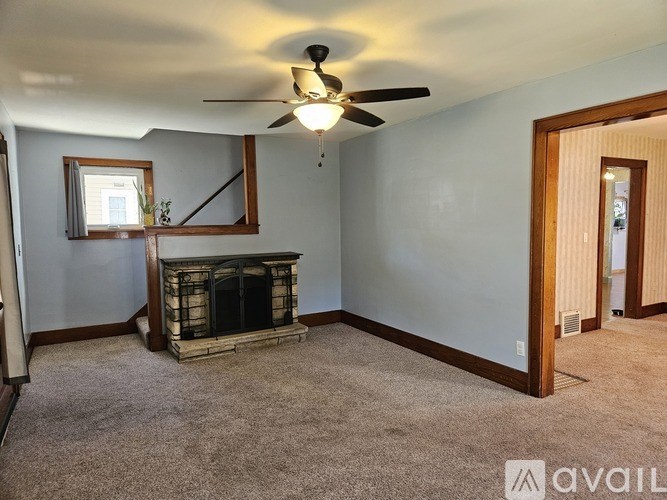 A living room with a fireplace and a ceiling fan.