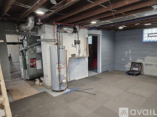 A room with a furnace and a large pipe running along the ceiling.