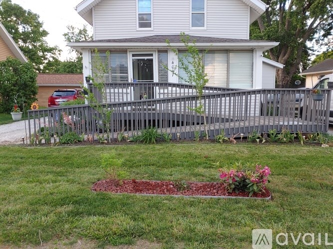 A house with a grey fence and a flower bed in front.