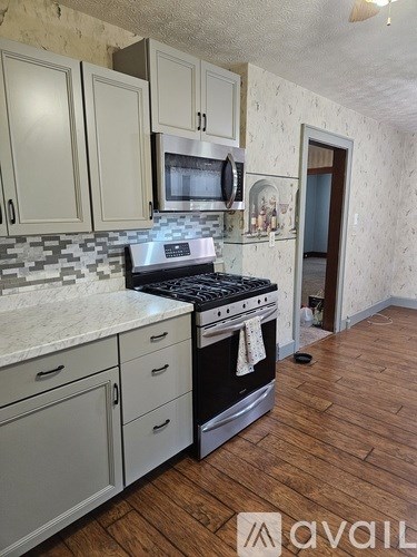 A kitchen with wooden floors and a black stove top oven.