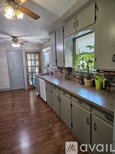 A kitchen with wooden floors and white cabinets.