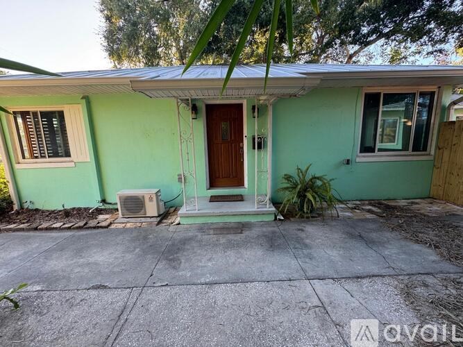 A green house with a brown door and a window with white trim.