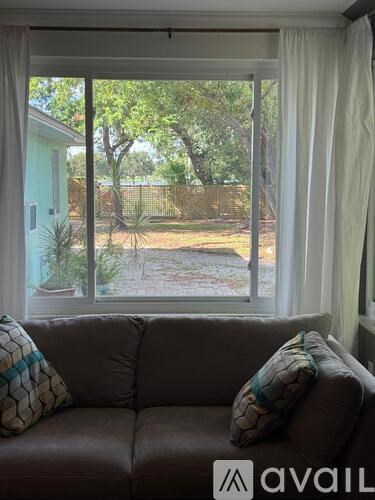 A living room with a couch and a window overlooking a backyard.
